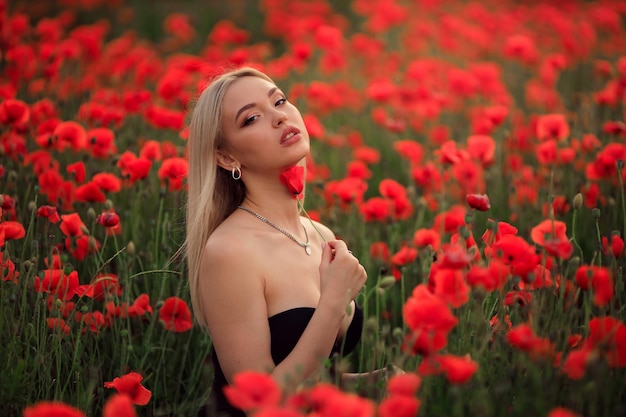 Retrato de uma linda mulher loira com um chapéu de palha ao pôr do sol em um campo de papoulas