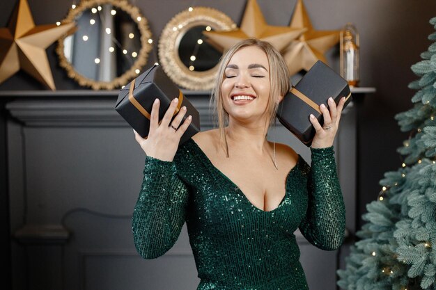 Retrato de uma linda mulher loira de vestido verde perto da árvore de Natal