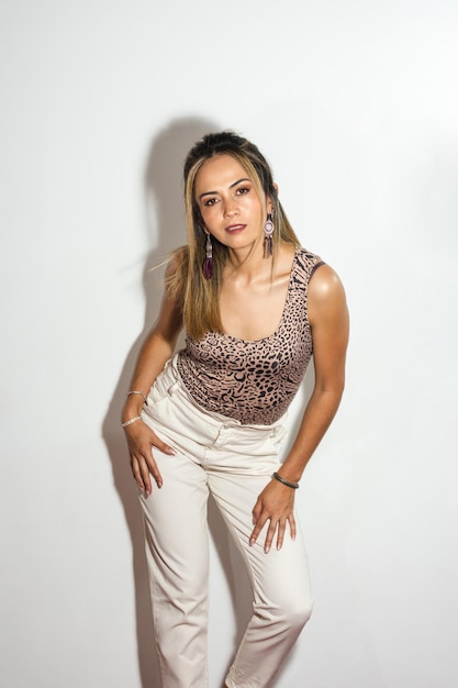 Retrato de uma linda mulher loira posando com atitude com uma parede branca ao fundo