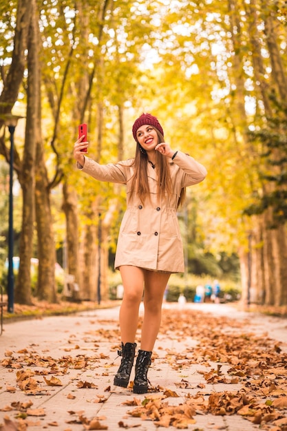 Retrato de uma linda mulher no outono ao lado de uma floresta na natureza fazendo uma videochamada