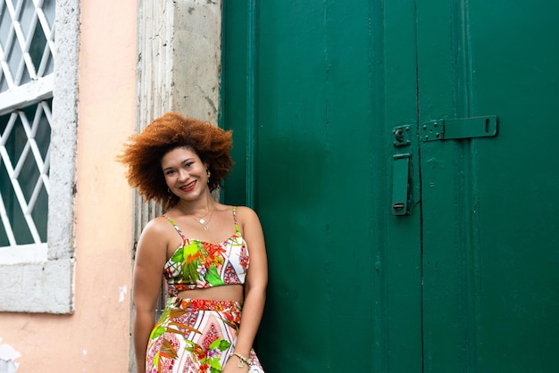 Retrato de uma linda mulher ruiva usando um vestido colorido encostado em uma porta verde Pessoa viajando