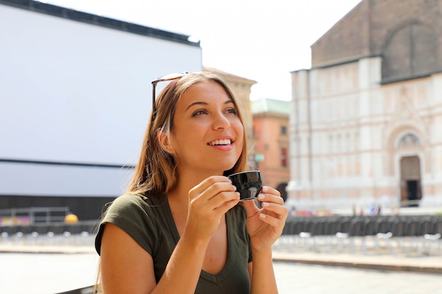 Retrato de uma linda mulher tomando café, sentado ao ar livre em um café italiano, desfrutando de sua viagem pela itália