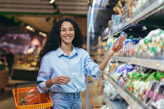 Retrato de uma linda mulher vegetariana no supermercado, uma mulher latino-americana escolhe vegetais para