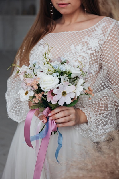 Retrato de uma linda noiva com um buquê de rosas brancas e margaridas cor  de rosa nas mãos em um interior leve | Foto Premium