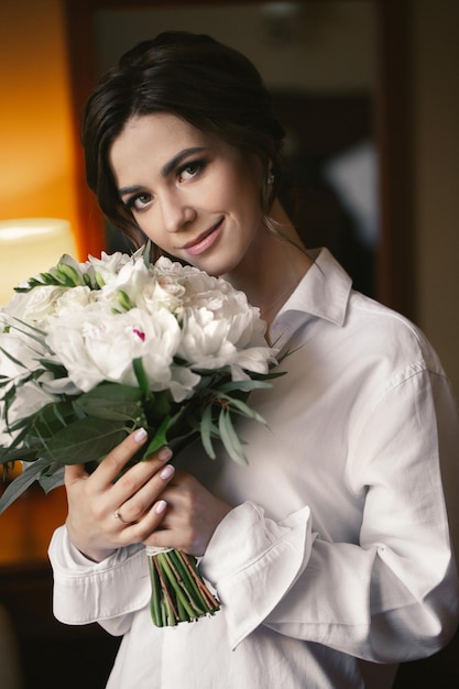 Retrato de uma linda noiva delicada em uma camisa branca com um buquê de casamento