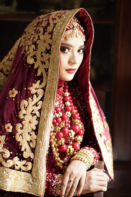 Foto retrato de uma linda noiva indiana em um vestido dourado e vermelho