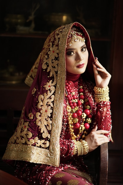 Foto retrato de uma linda noiva indiana em um vestido dourado e vermelho