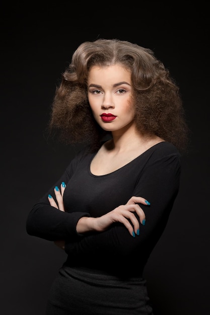 Retrato de uma linda senhora olhando para a câmera e posando com os braços cruzados ou dobrados, isolados no preto