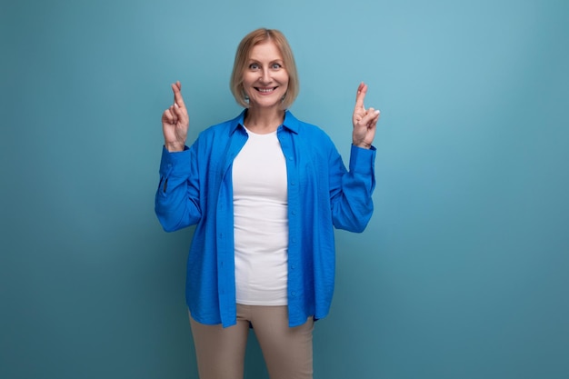 Retrato de uma loira atraente de meia-idade em uma camisa elegante casual sobre um fundo azul com