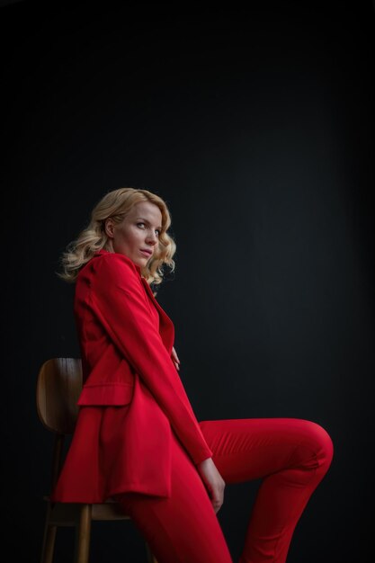 Retrato de uma loira autêntica e elegante modelo sexy posando de sutiã e terninho vermelho no estúdio