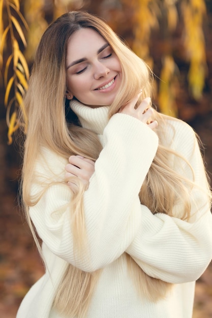 Retrato de uma loira encantadora com um sorriso lindo garota de suéter branco