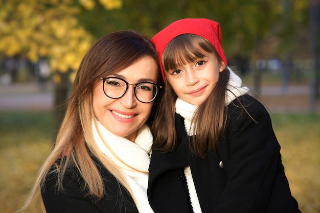 Retrato de uma mãe feliz linda e positiva abraçando sua filha pequena e linda menina