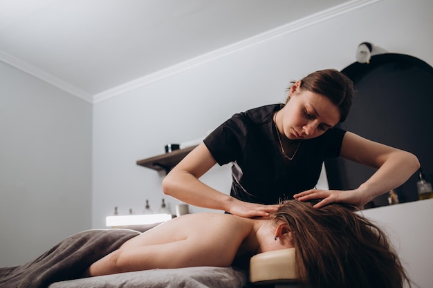 Retrato de uma massagista profissional fazendo massagem terapêutica para seu cliente na clínica Conceito de relaxamento e cuidados com o corpo
