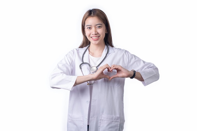 Retrato de uma médica asiática vestindo uniforme fazendo forma de coração com mãos isoladas em fundo branco