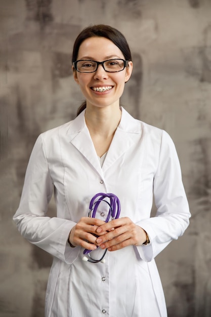 Retrato de uma médica com estetoscópio, olhando para a câmera, sorrindo médica em uma clínica