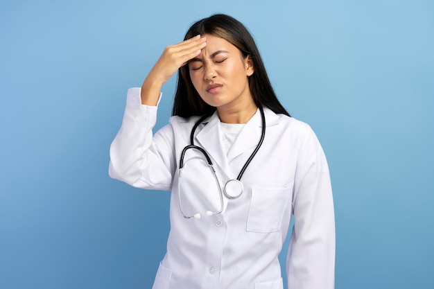 Retrato de uma médica deprimida chateada esfregando a cabeça e sentindo dor de cabeça
