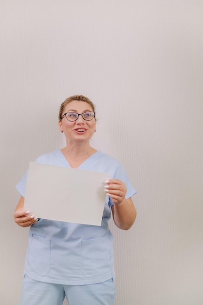 Retrato de uma médica em uma túnica azul segurando uma folha branca em branco