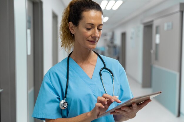 Foto retrato de uma médica mestiça em pé no corredor do hospital usando tablet