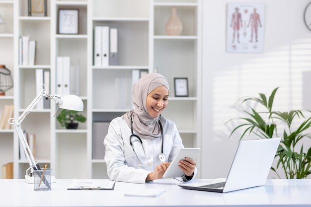 Retrato de uma médica muçulmana em hijab, uma médica com um tablet usando um aplicativo sorridente