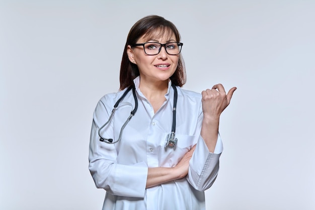 Retrato de uma médica olhando para a câmera falando gesticulando no fundo claro do estúdio