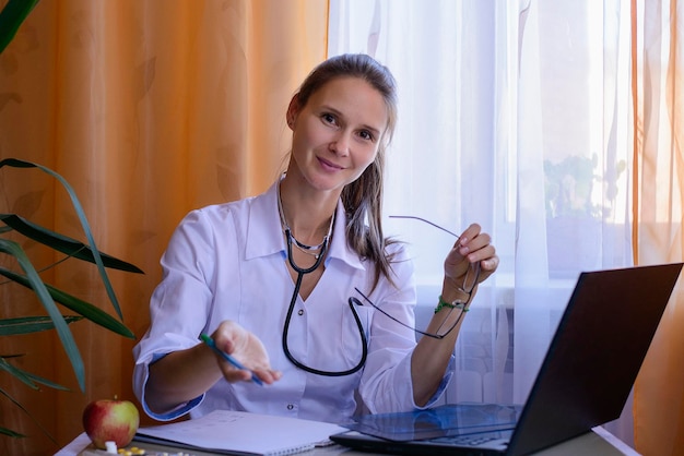 Retrato de uma médica segurando um raio-X enquanto está sentada na mesa