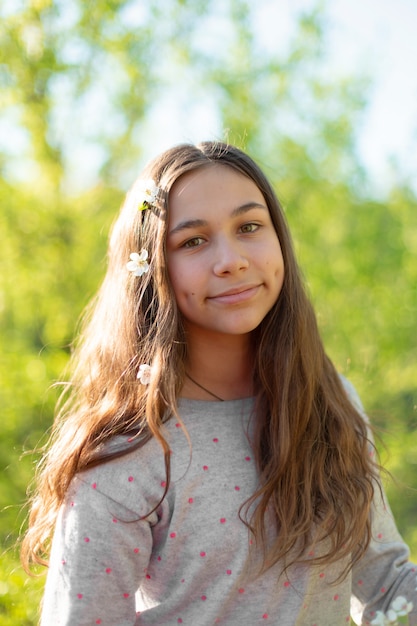 Foto retrato de uma menina adolescente bonita em um jardim de primavera verde florescendo