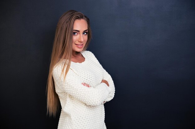 Retrato de uma menina adorável e feliz em pé com os braços cruzados sobre o espaço cinza