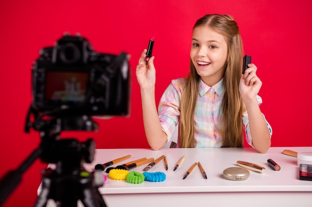 Retrato de uma menina adorável filmando-se à mesa com cosméticos