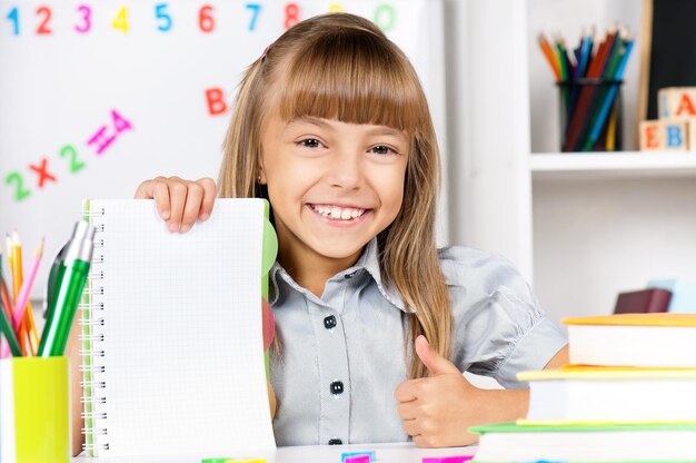 Retrato de uma menina adorável na escola na secretária