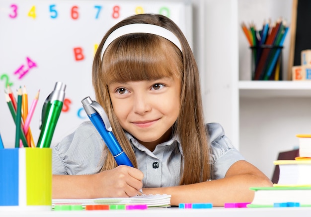 Retrato de uma menina adorável na escola na secretária