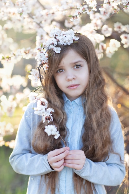 Retrato de uma menina ao lado de uma árvore de florescência e segurando um ramo de flores