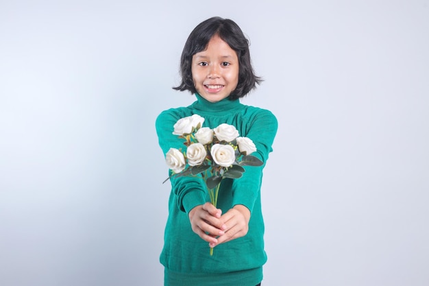 Retrato de uma menina asiática segurando um buquê de rosas brancas em fundo cinzento