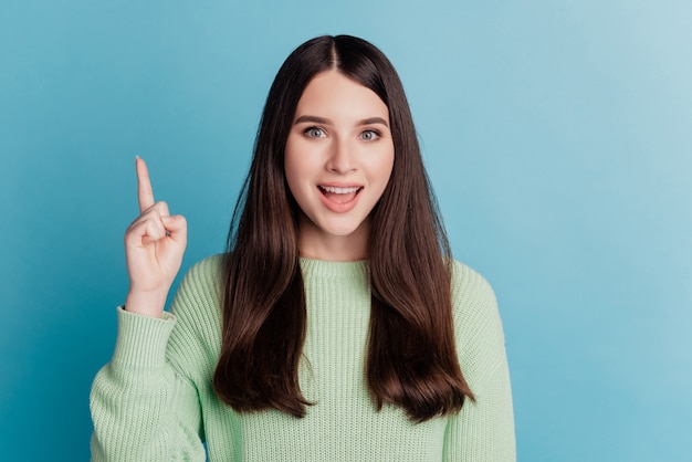 Retrato de uma menina bonita apontando o dedo para longe do rosto animado sugere um banner de espaço vazio