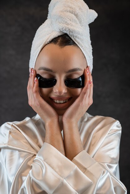Retrato de uma menina bonita caucasiana com adesivo de hidrogel de colágeno aplicado sob o olho isolado em preto