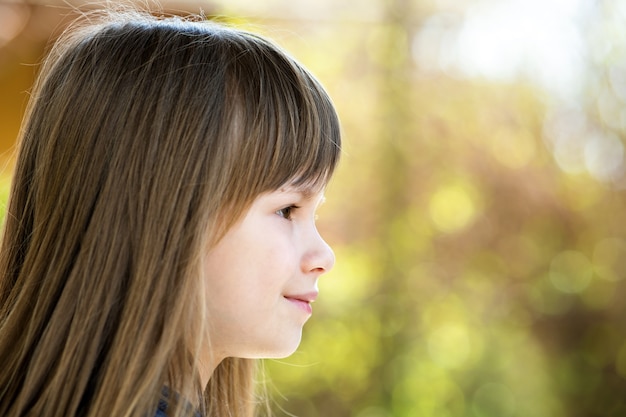 Foto retrato de uma menina bonita com olhos cinzentos e cabelo longo loiro sorrindo ao ar livre