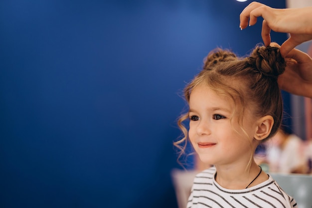 Retrato de uma menina bonita com um penteado elegante em um salão de beleza O processo de fazer o cabelo de uma criança