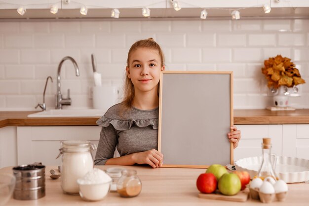 Foto retrato de uma menina bonita de pé na cozinha