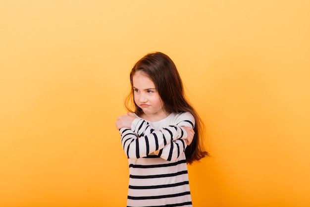 Retrato de uma menina bonita e confiante mostrando emoções e polegares para cima isolados em amarelo