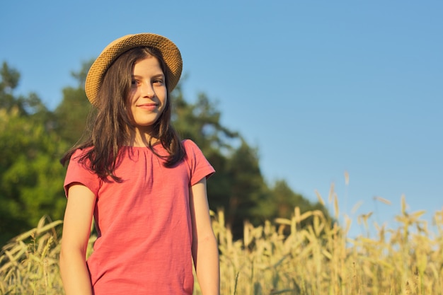 Retrato de uma menina bonita no chapéu no campo de trigo