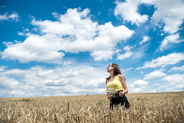 Retrato de uma menina bonita posando no fundo de um campo agrícola, horário de verão