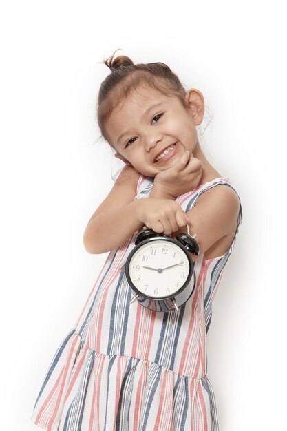 Foto retrato de uma menina bonita segurando um despertador contra um fundo branco