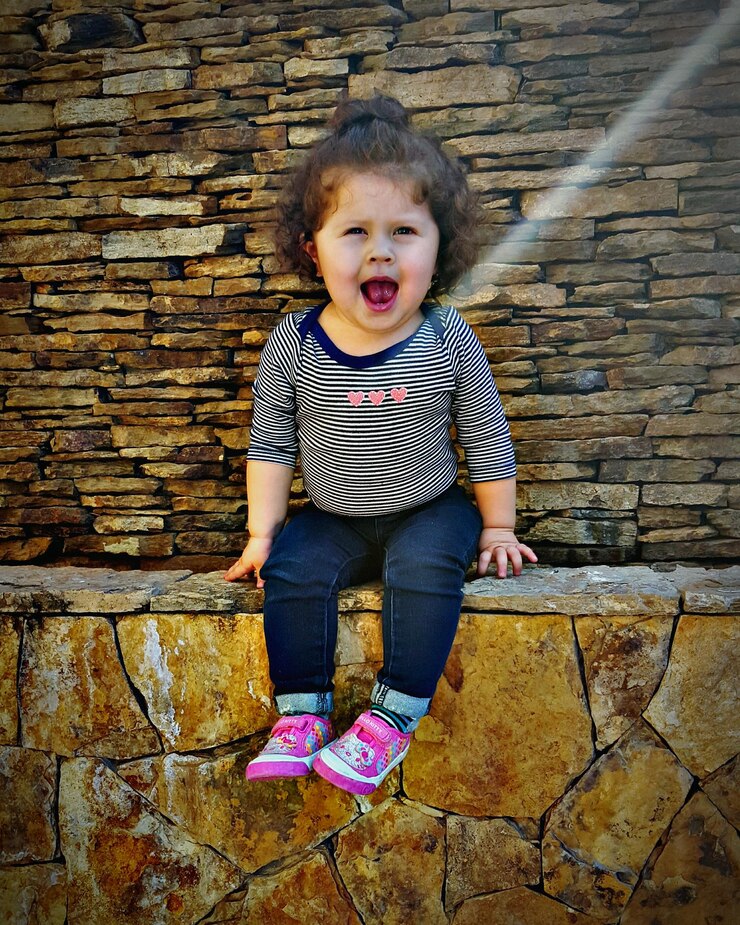 Foto retrato de uma menina bonita sentada em uma parede de contenção