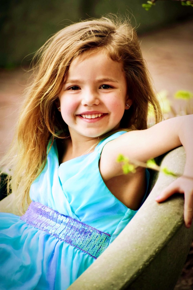 Foto retrato de uma menina bonita sorridente sentada ao ar livre