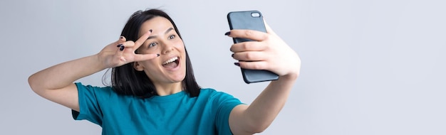 Retrato de uma menina bonita tirando uma selfie isolada sobre fundo cinza