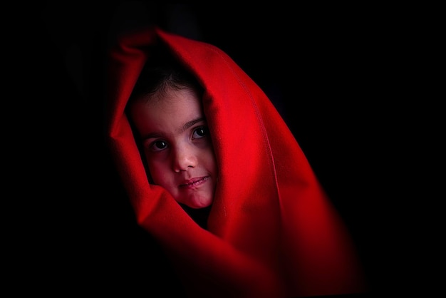 Foto retrato de uma menina bonita usando um lenço vermelho contra um fundo preto