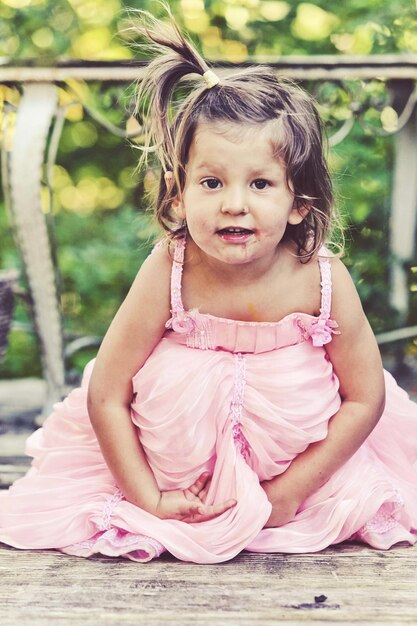 Foto retrato de uma menina bonita vestindo um vestido rosa em uma tábua de madeira