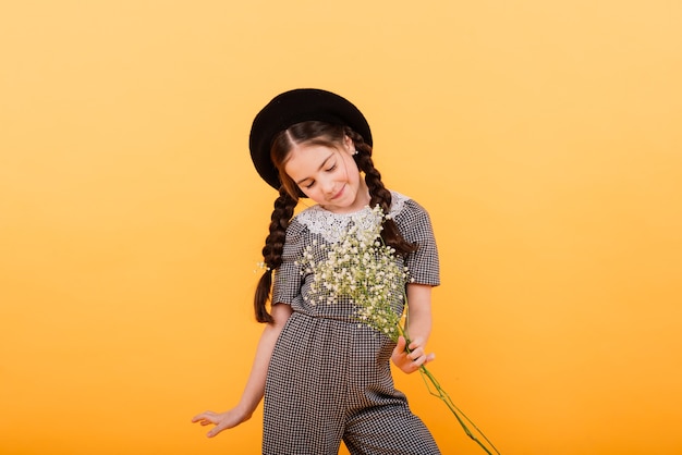 Retrato de uma menina bonitinha com buquê de flores no estúdio em fundo amarelo. parabéns, primavera ou conceito de férias felizes. copie o espaço para o texto