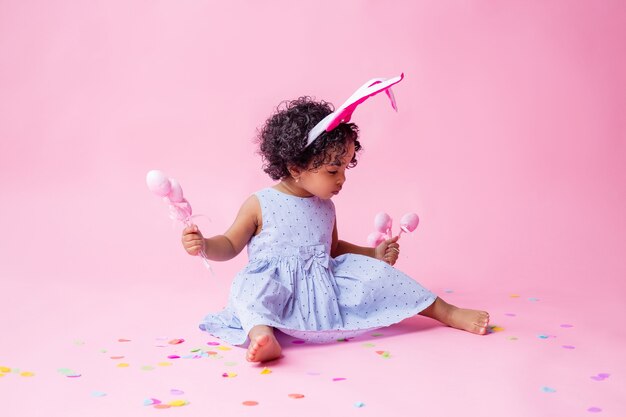 retrato de uma menina bonitinha com orelhas de coelhinho da Páscoa na cabeça segurando ovos de Páscoa. estúdio, fundo rosa