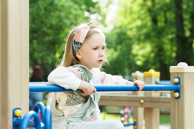 Retrato de uma menina bonitinha. Criança brincando em um playground em um parque da cidade.