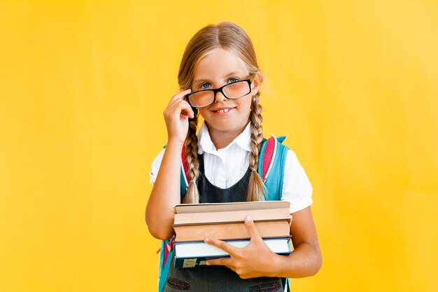 Retrato de uma menina bonitinha em um fundo amarelo. A colegial está olhando para a câmera,